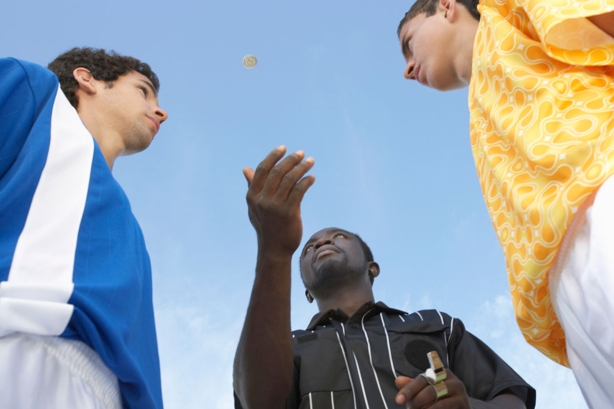 A referee observes the coin toss at a soccer game. 