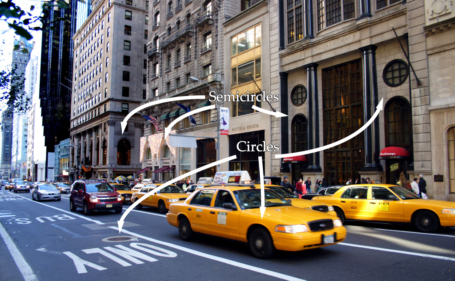 An image of a street in New York that has many different shapes including a circular sewer grates and semicircular windows.