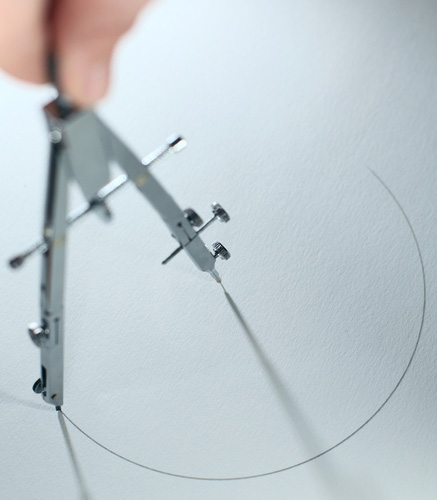 A person drawing a circle with a compass.