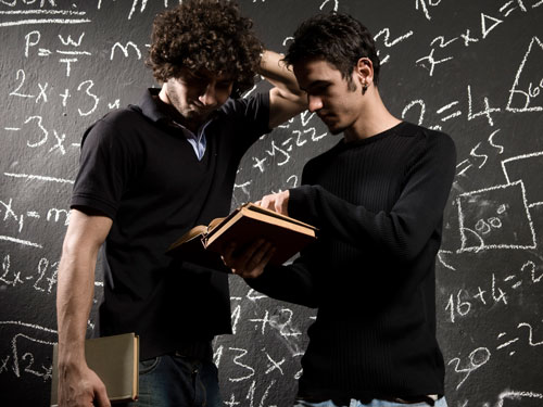 Two students studying in front of a chalkboard.