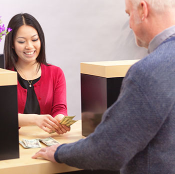 An customer making a financial transaction with a bank teller over the counter in a retail bank.