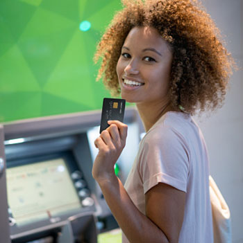 Woman at ATM holding a bank card.
